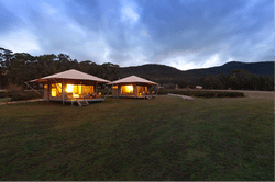 Image of two glamping tents with their lights on during early evening at Cave Hill Creek