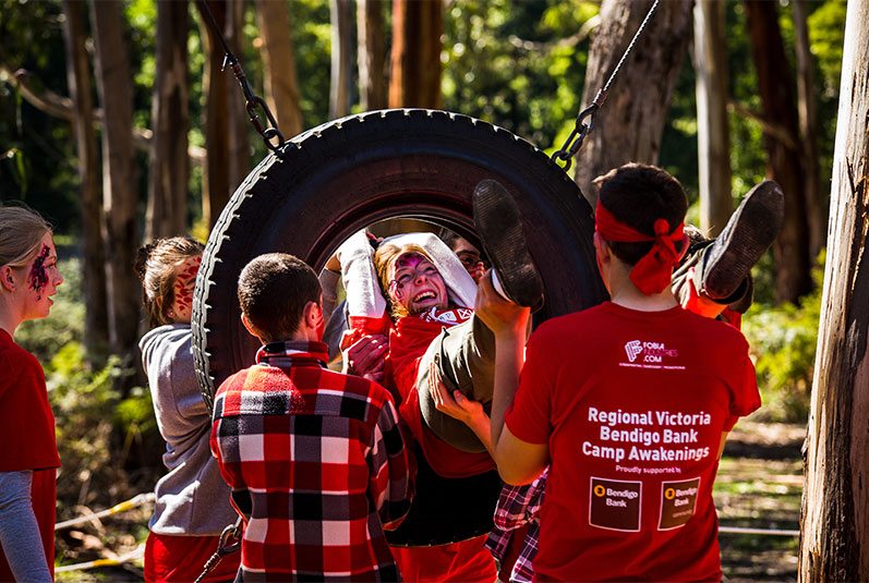 Regional Victoria Bendigo Bank Camp Awakenings group activity featuring person being helped through a suspended tyre