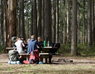 Group of children sitting at a campsite table with hiking bags and water bottles