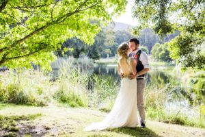 Wedding photo of couple standing under trees next to Cave Hill Creek