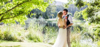Wedding photo of couple standing under trees next to Cave Hill Creek