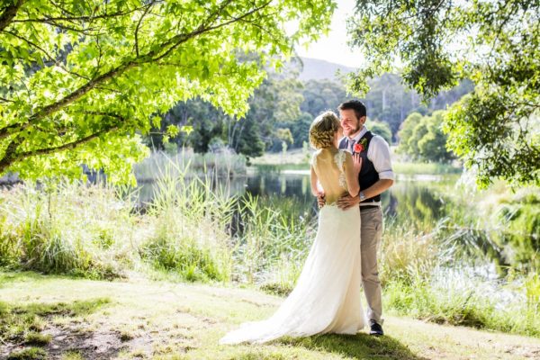 Wedding photo of couple standing under trees next to Cave Hill Creek