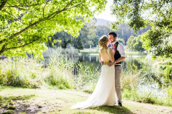 Wedding photo of couple standing under trees next to Cave Hill Creek