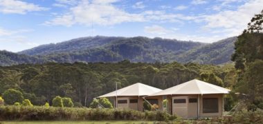 Image of two beige clamping tents at Cave Hill Creek with tree covered hills in background