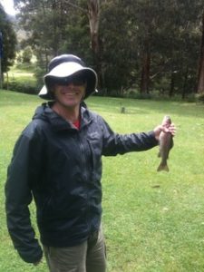 Image of smiling man holding the fish he caught at Cave Hill Creek