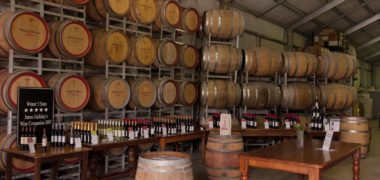 Stacked Michael Unwin wine barrels with bottles of unopened wines showcased on tables.