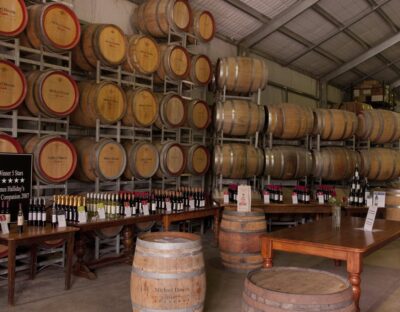 Stacked Michael Unwin wine barrels with bottles of unopened wines showcased on tables.