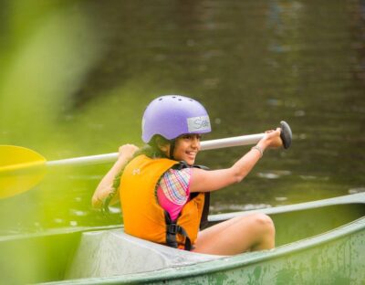 Image of smiling girl paddling a canoe in Cave Hill Creek