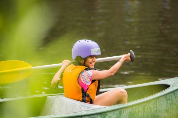 Image of smiling girl paddling a canoe in Cave Hill Creek