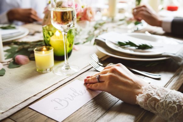 Close up image of wedding table setup with bride's hand touching a 'Bride' placement card