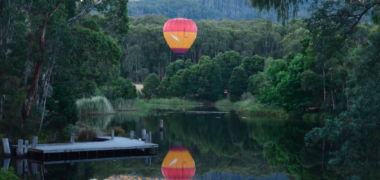 Image of hot air balloon rising in the air above Cave Hill Creek in early morning