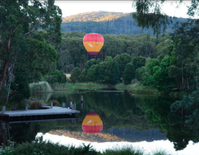 Image of hot air balloon rising in the air above Cave Hill Creek in early morning
