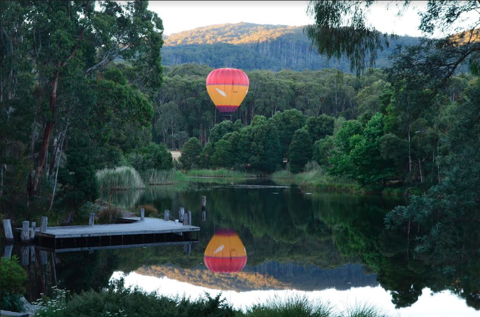 Image of hot air balloon rising in the air above Cave Hill Creek in early morning