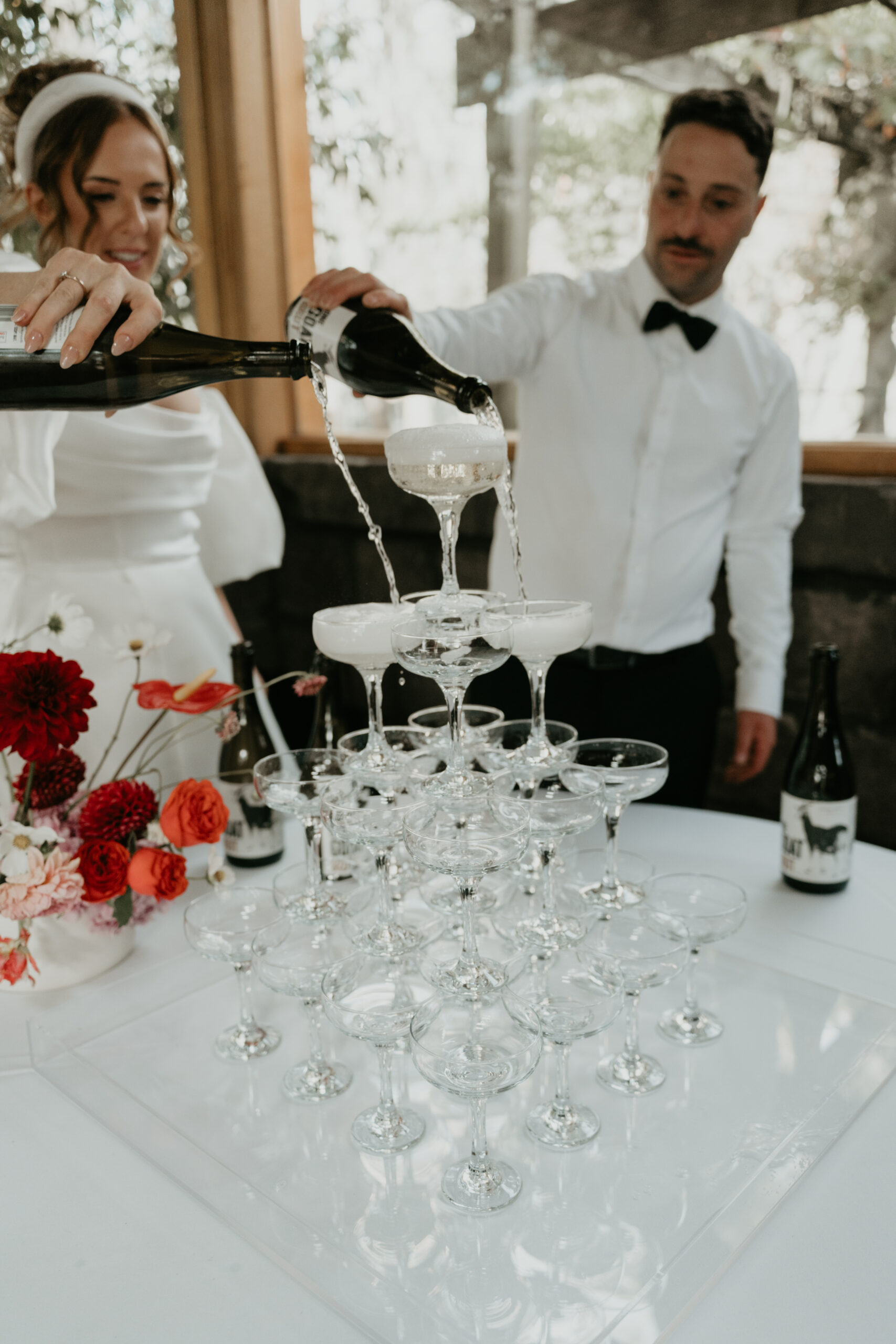 Bride and groom pouring bottles of champagne on a champagne tower at a wedding reception